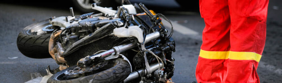 Crashed motorcycle after road accident with a car on a city street