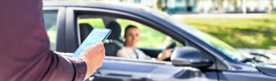 Customer waiting driver to pick up on city street. Man holding smartphone. Mobile and online booking for rideshare transportation with cellphone.