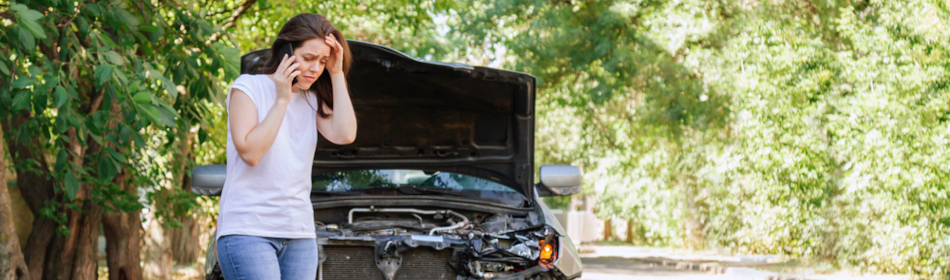 woman on cell phone after car has been involved in a hit and run accident