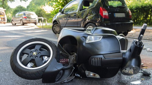Scooter laying in the road after being hit by a car