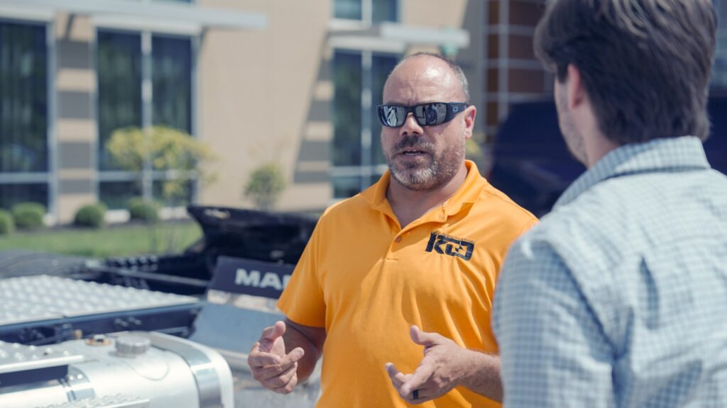 man standing in front of parked semi giving demonstration
